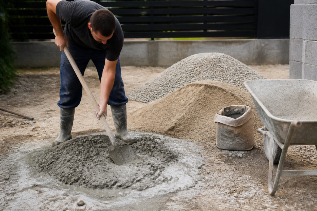 Dosage du béton en pelle sur chantier avec sable, gravier et un sac de ciment
